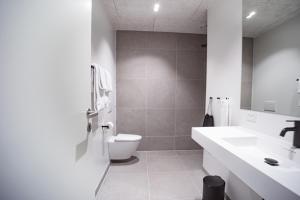a white bathroom with a toilet and a sink at Hotel Djurhuus in Tórshavn
