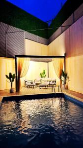 a swimming pool with two benches and a table and a couch at Villa luxueuse in Tipaza