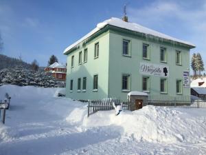 ein grünes Gebäude im Schnee mit einem Zaun in der Unterkunft Guest House Marzebilla Pernink in Pernink