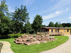 a log cabin with a large rock in the yard at Kingfisher in Ross on Wye