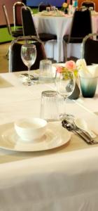 a table with a white plate and glasses on it at Barn Talaepu Resort in Ban Suan Khat