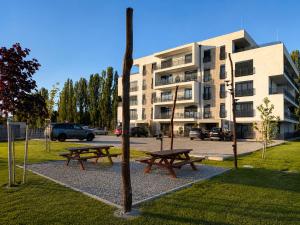 two picnic tables in a park in front of a building at Rivapark in Dunajská Streda