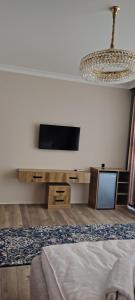 a bedroom with a tv and a bed and a chandelier at AMARANT hotel in Baysun