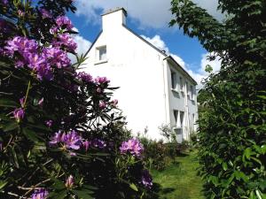 ein weißes Gebäude mit lila Blumen davor in der Unterkunft Grand lodge du Pin 15 pers & salle fêtes in Languidic