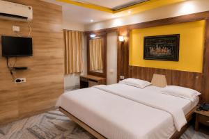 a bedroom with a large white bed and a tv at Hotel kabras' inn in Mount Ābu