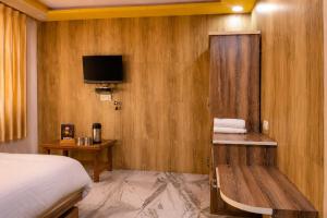 a hotel room with a bed and a tv on a wall at Hotel kabras' inn in Mount Ābu