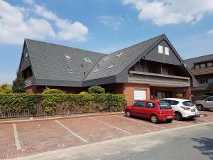 a house with two cars parked in a parking lot at Wattliebe Burhave in Burhave