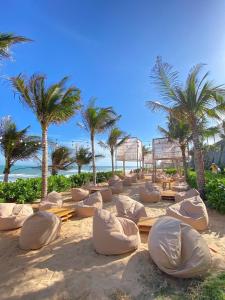a beach with chairs and palm trees and the ocean at Apec Mandala Ocean Retreat- Mui Ne in Mui Ne