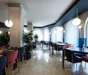 ein Esszimmer mit Tischen, Stühlen und Fenstern in der Unterkunft Il Palazzin Hotel in St Paul's Bay
