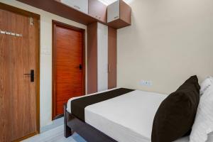 a bedroom with a bed and a wooden door at Hotel O The Royal Guest Rooms in Vijayawāda