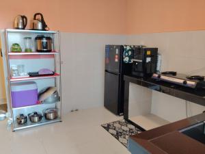 a kitchen with a black refrigerator next to a shelf at Teratak Saharah Homestay in Port Dickson
