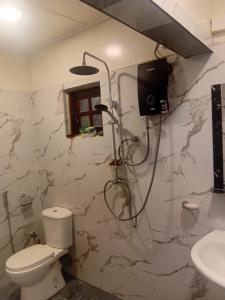 a bathroom with a shower with a toilet and a sink at Trailside Homestay in Badulla