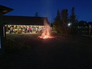 a fire in a yard at night with people standing around at Fenix Grzybno pokoje pracownicze, rodzinne, typu standard,dłuższe pobyty in Grzybno