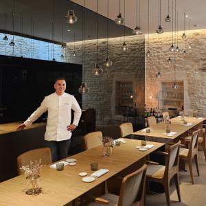 a man is standing in a restaurant with tables at Hôtel de Tourrel, Saint Rémy de Provence, a Member of Design Hotels in Saint-Rémy-de-Provence