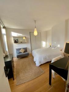 a bedroom with a large white bed and a chair at Les Jardins Suspendus in Lyon