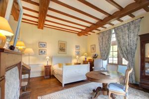 a bedroom with a bed and a table and a fireplace at La Gaubertière in Saint-Paul-du-Bois
