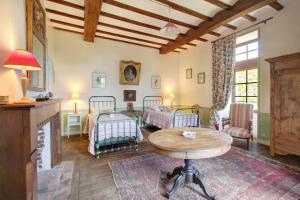 a living room with two beds and a table at La Gaubertière in Saint-Paul-du-Bois
