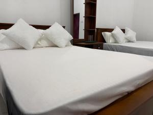 two beds with white sheets and pillows in a room at Yala Dream Guest House in Tissamaharama