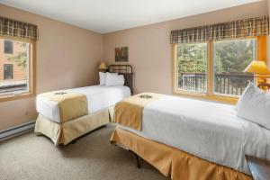 two beds in a room with two windows at Mountain House, A Vail Resorts Property in Keystone