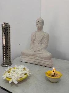 a statue of a buddha sitting next to a candle at Yala Dream Guest House in Tissamaharama