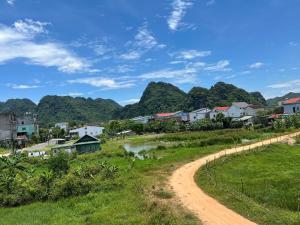 a dirt road through a village with mountains in the background at An Binh Homestay in Phong Nha