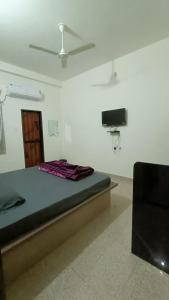 a bedroom with a bed and a tv on the wall at Hotel Deeksha in Mandlā