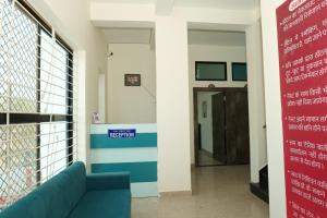 a hallway of a hospital with a blue couch at Hotel Deeksha in Mandlā