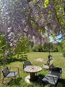 a picnic table and chairs under a tree with purple flowers at ATELIER Gîte Cahors in Pradines +5 photos