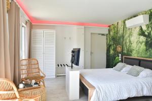 a bedroom with a bed and a large painting on the wall at Suite Aracari, clim, balneo, terrasse - Parc des Oiseaux in Villars-les-Dombes