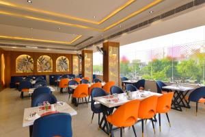 a restaurant with tables and chairs and a large window at Ginger Kota, Vishwakarma Nagar in Kota