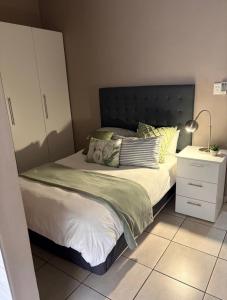 a bedroom with a large bed and a night stand at Grey Corner Guesthouse in Postmasburg +14 photos