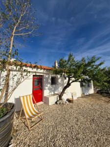 a house with a red door and a chair at Casa Nossa in Azinhal