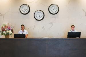 two people sitting at a counter with clocks on the wall at Anthea Hotel Apartments in Ayia Napa
