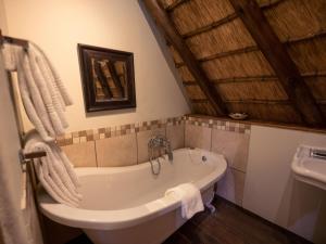 a bathroom with a bath tub and a sink at Hluhluwe Lodge by ANEW in Hluhluwe