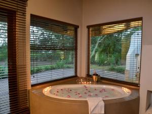 a bath tub in a room with two windows at Hluhluwe Lodge by ANEW in Hluhluwe