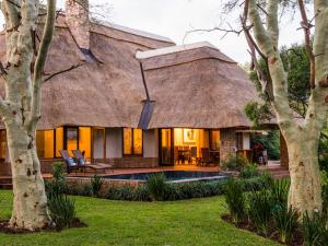a house with a thatched roof and a swimming pool at Hluhluwe Lodge by ANEW in Hluhluwe