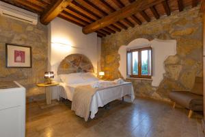 a bedroom with a bed and a stone wall at Le Querciolaie with Geothermal Pool - by PosarelliVillas in Monteverdi Marittimo +242 photos