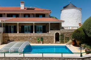 a swimming pool in front of a house with a lighthouse at Moinhos Da Guimaroa in Cadafais