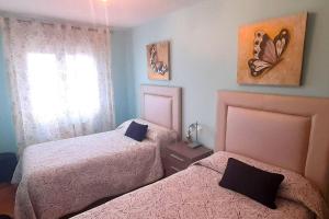a bedroom with two beds and a butterfly painting on the wall at Apartamento Playa Foz in Foz
