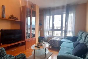 a living room with a blue couch and a tv at Apartamento Playa Foz in Foz