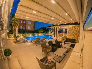a patio with chairs and tables and a swimming pool at Apartments Sun Dance 2 with heated Pool in Novalja