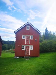 a red barn with red doors on a green field at Lægran Gård in Steinkjer