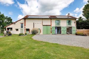 a large white house with green doors and a yard at Les Malvaux - Chambres d'hôtes in Huriel