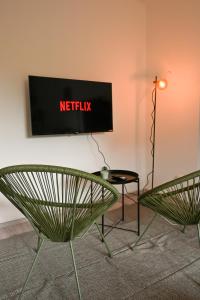 two green chairs and a television on a wall at Stilvolles Apartment im Bochumer Stadtkern in Bochum