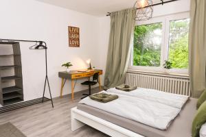 a bedroom with a bed and a desk and a window at Stilvolles Apartment im Bochumer Stadtkern in Bochum