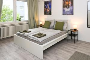 a white bedroom with a large white bed with green pillows at Stilvolles Apartment im Bochumer Stadtkern in Bochum