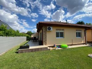 a small house with a green yard next to a fence at Deák Apartman Gárdony in Gárdony