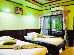 two beds in a room with green walls at Saiyok River House in Sai Yok +90 photos