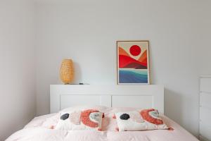 a white bedroom with a bed with two pillows at Le Cocon d'Achères in Achères