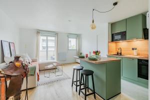 a kitchen with green cabinets and a living room at Le Cocon d'Achères in Achères